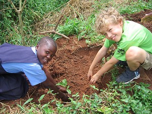 Children from Uganda and UK planting seeds together